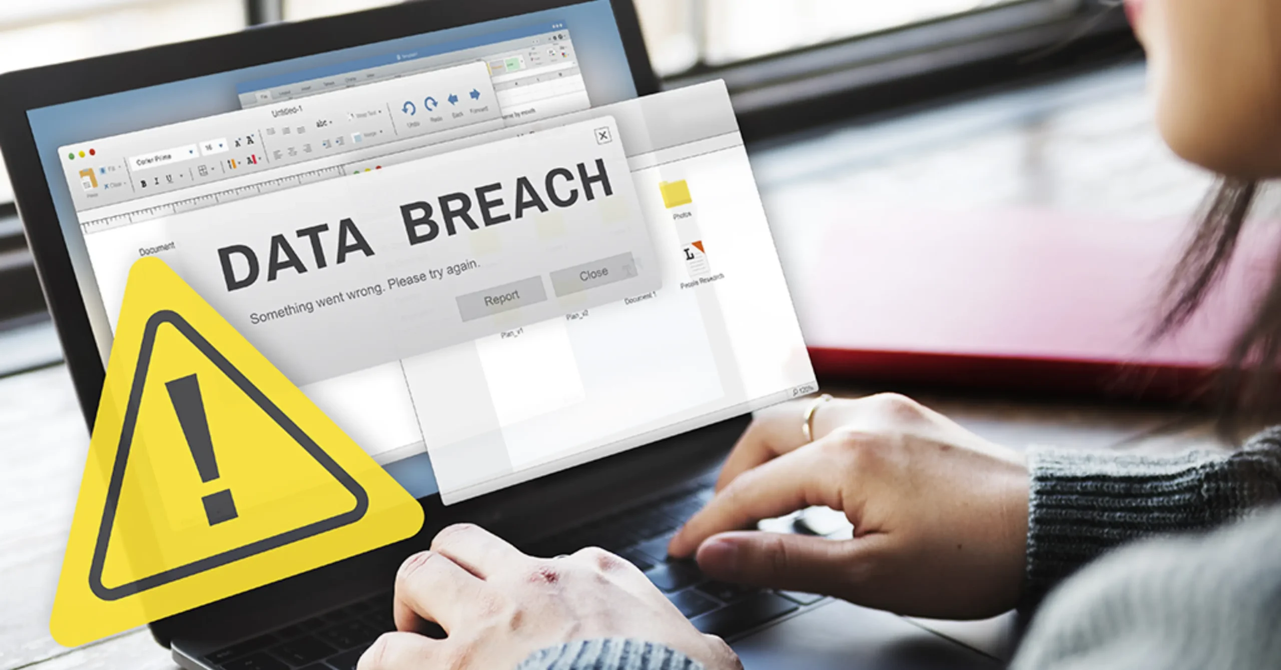 A person using a laptop sees a large warning sign and an alert message on the screen reading DATA BREACH, indicating a security incident or compromised information.